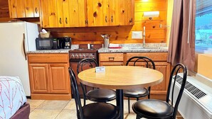 A kitchen with wooden cabinets, a stove, a microwave, and a dining table with chairs.