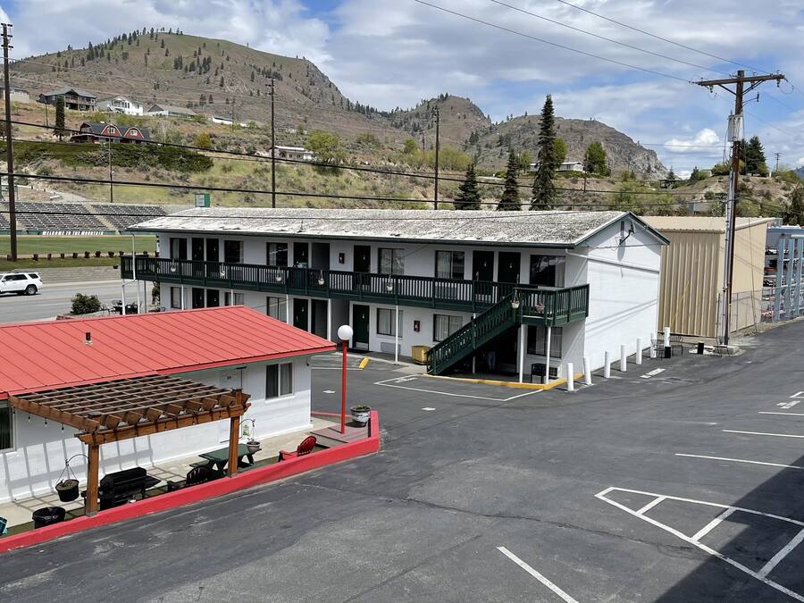 Um edifício com telhado vermelho, varanda e estacionamento.