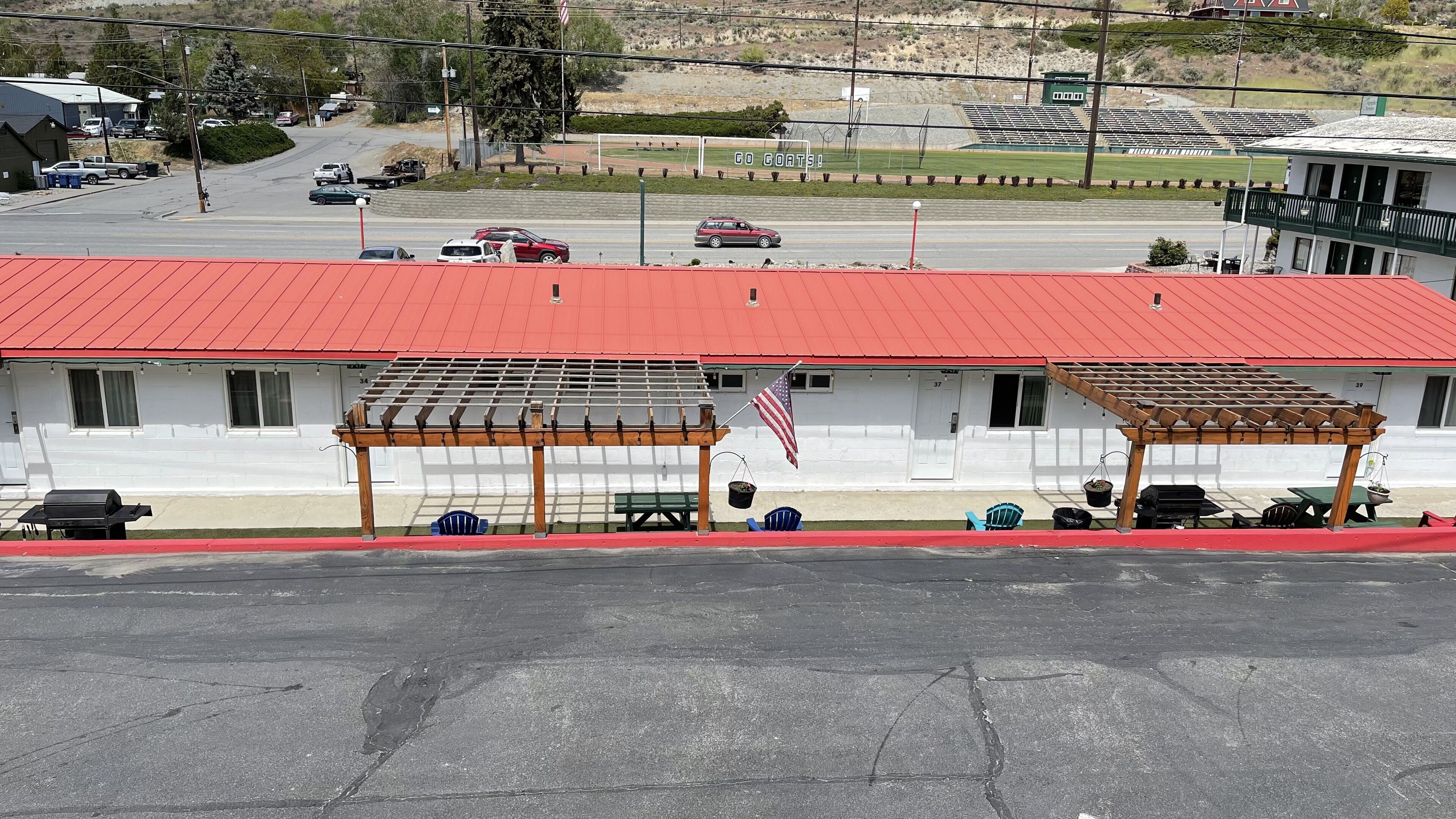 Un edificio con techo rojo, un porche cubierto con una pérgola y una bandera estadounidense.