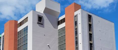A modern building with a flat roof, large windows, and a distinct orange and grey color scheme.