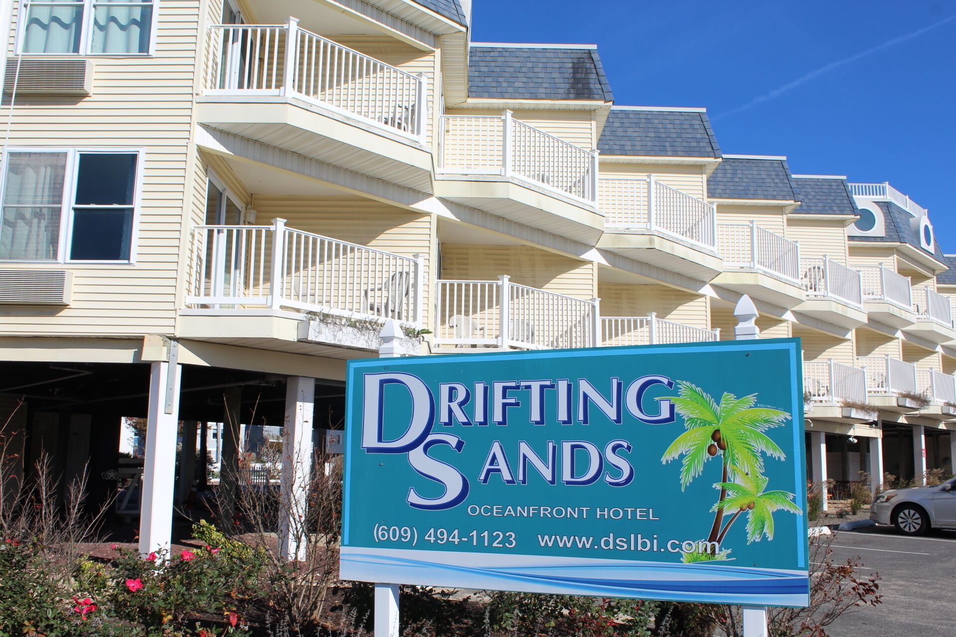 A hotel sign for Drifting Sands Oceanfront Hotel with a contact number and website.