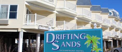 En hotellskylt för Drifting Sands Oceanfront Hotel, med ett telefonnummer och en webbadress.