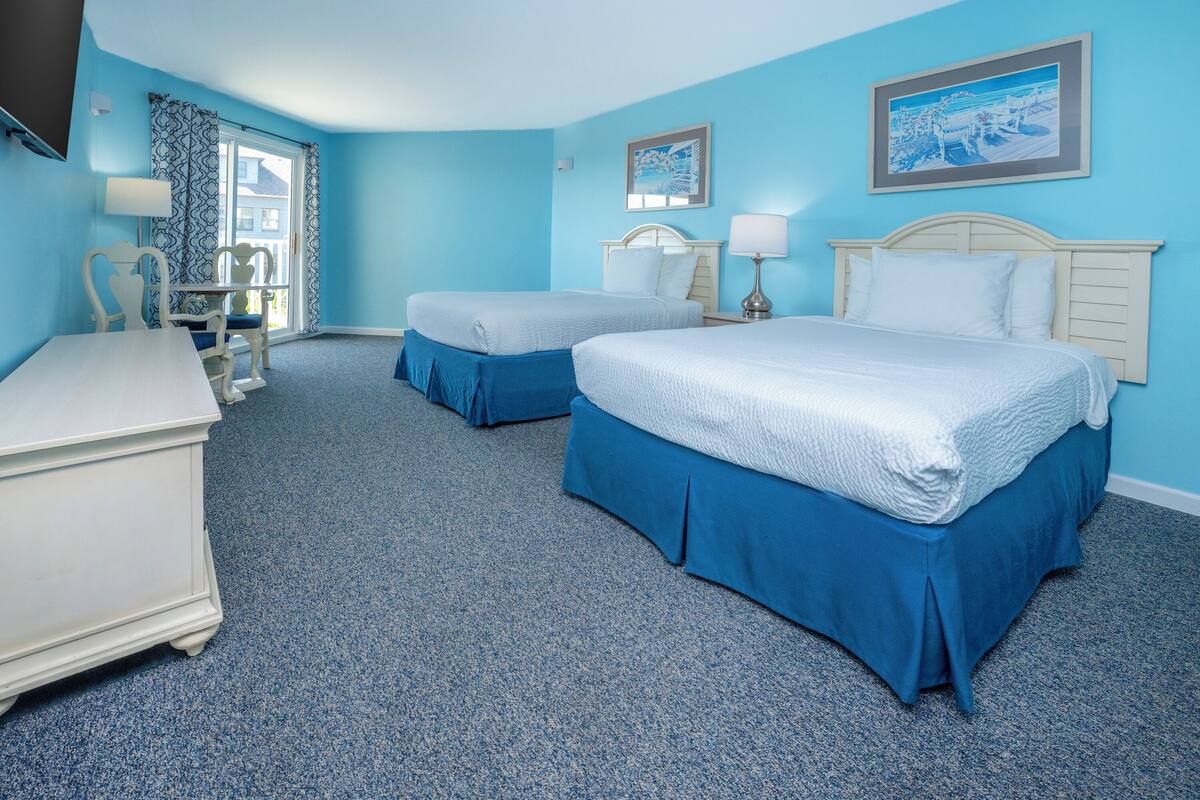 A hotel room with two beds, a desk, and a chair.