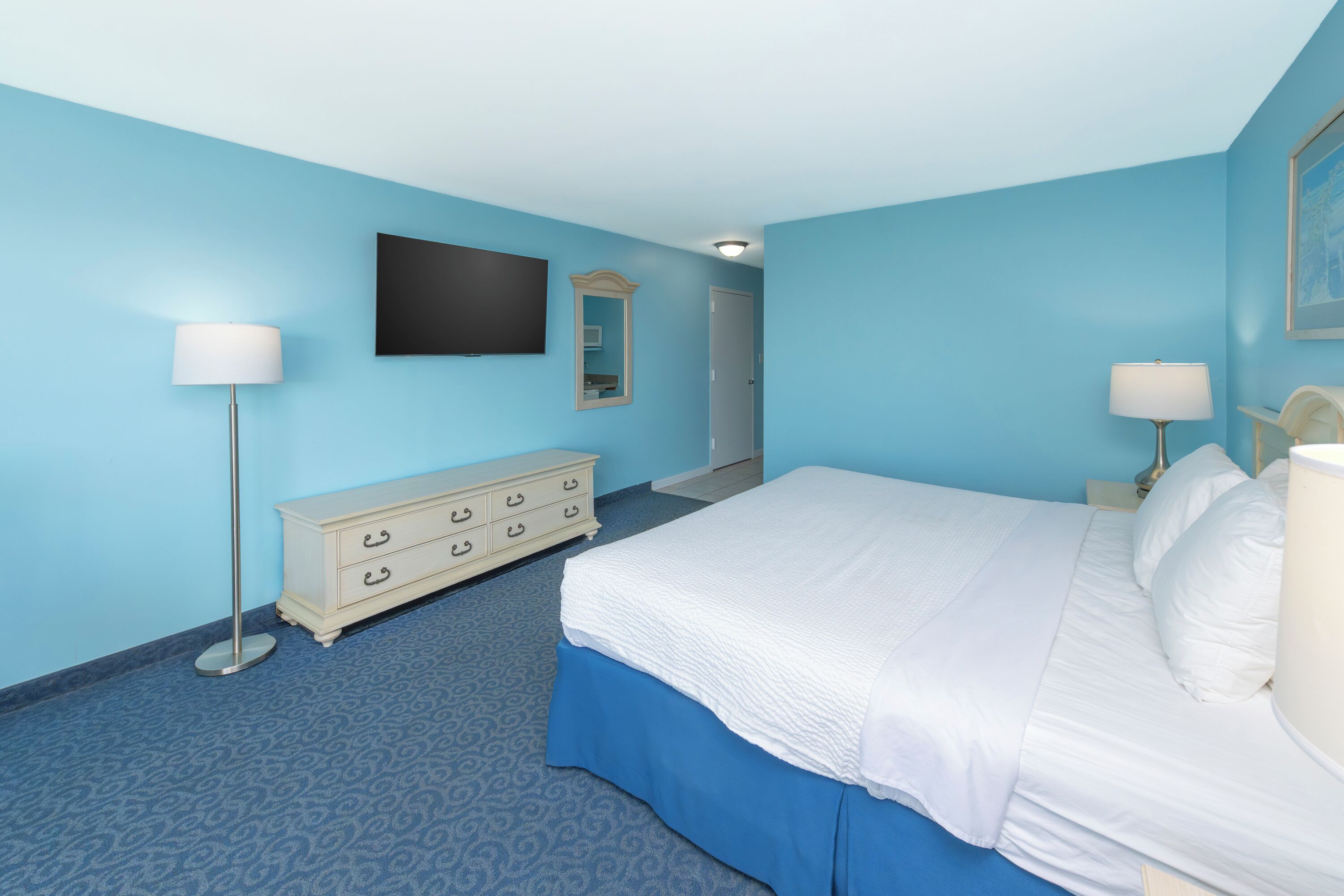 A bedroom with a bed, dresser, and two lamps.