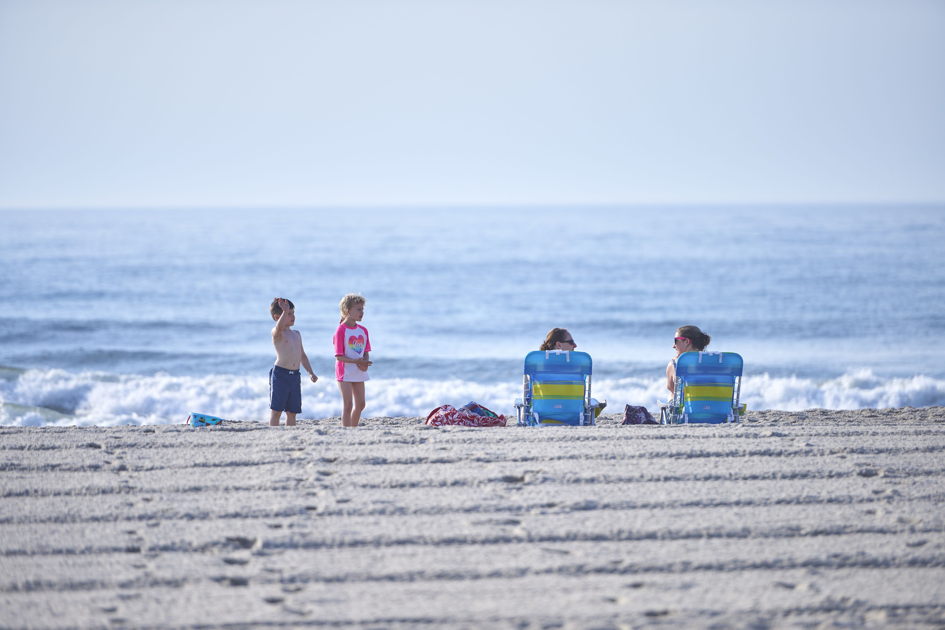 A beach with people and beach chairs.
