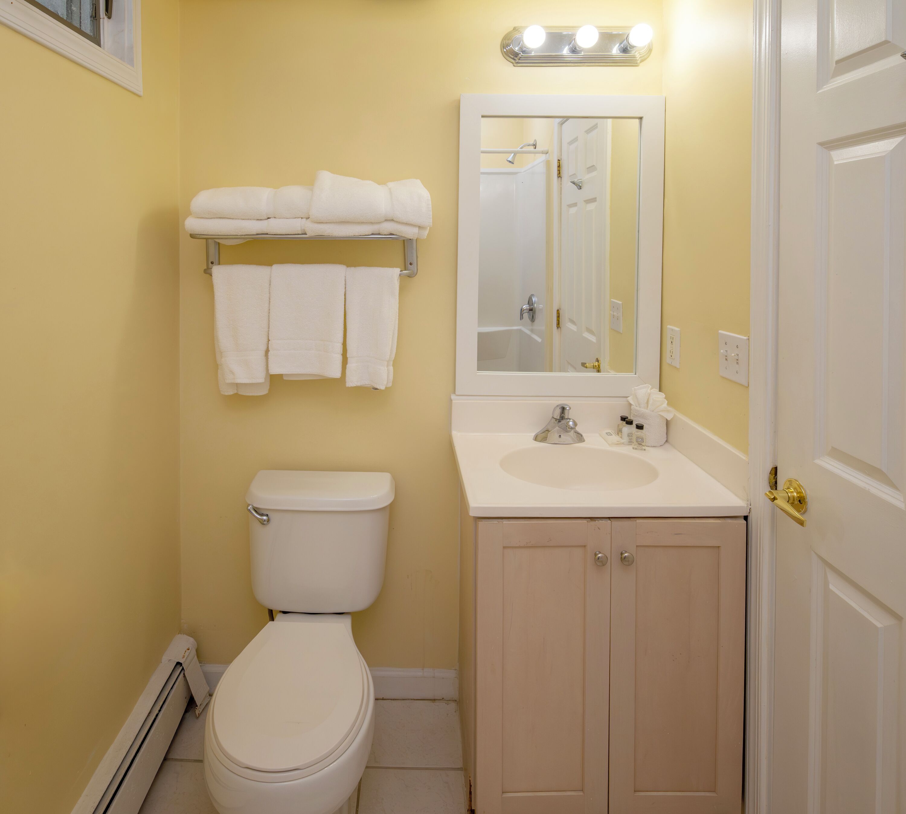 A bathroom with a toilet, sink, and mirror.
