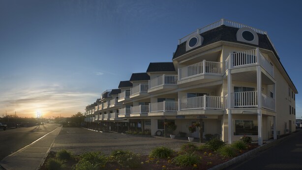 Un hotel de varios pisos con balcones, un estacionamiento y vistas al atardecer.