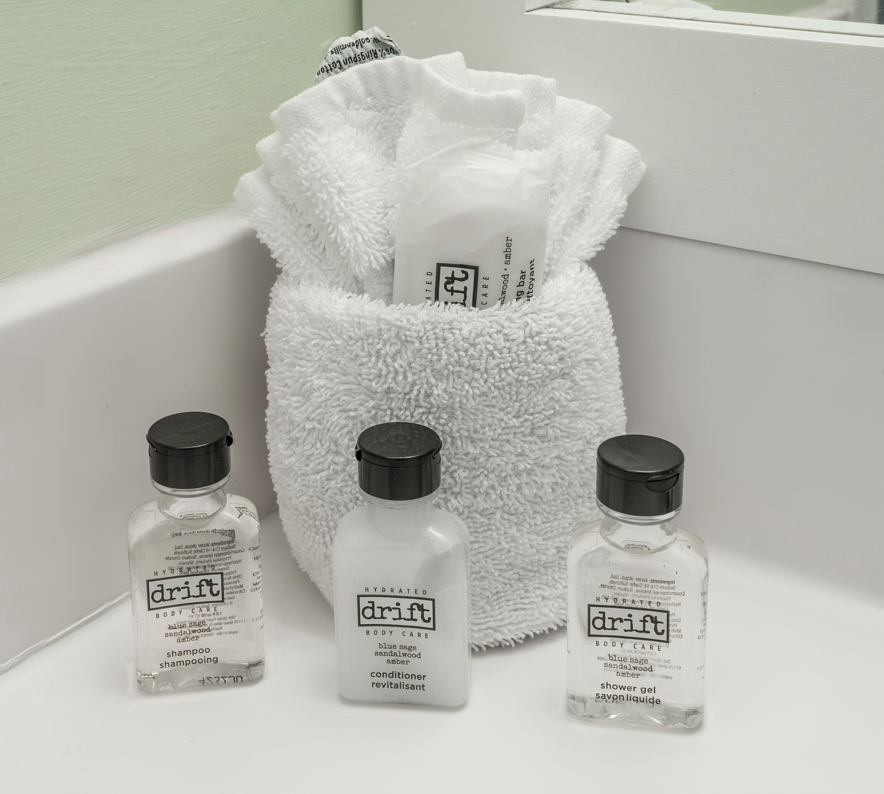 Three bottles of Drift body care products and a white towel on a white surface.