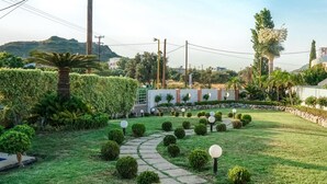 Un jardín bien cuidado con un sendero de piedra, arbustos podados y una variedad de árboles.