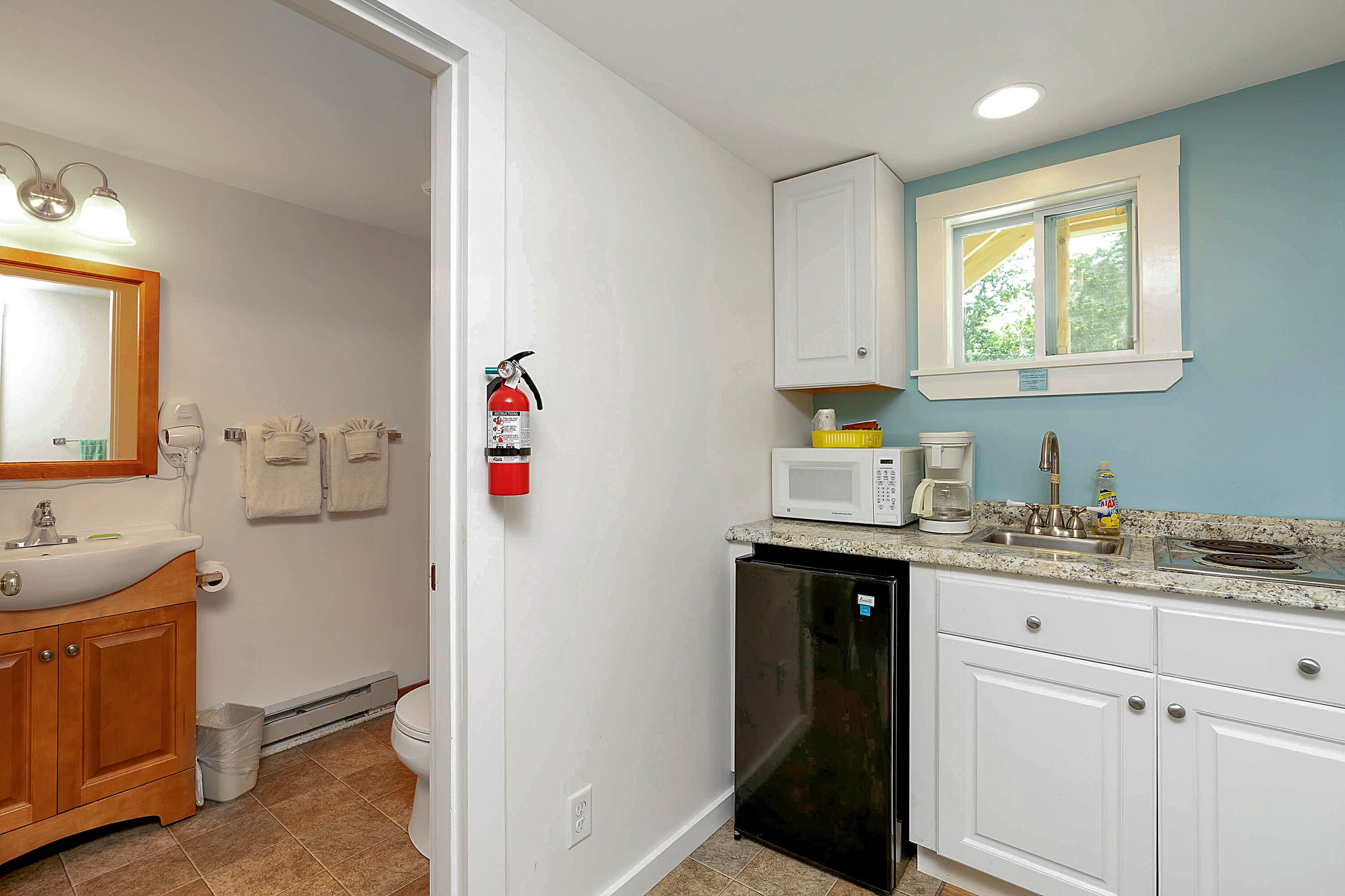 A kitchen with white cabinets, a microwave, and a sink.