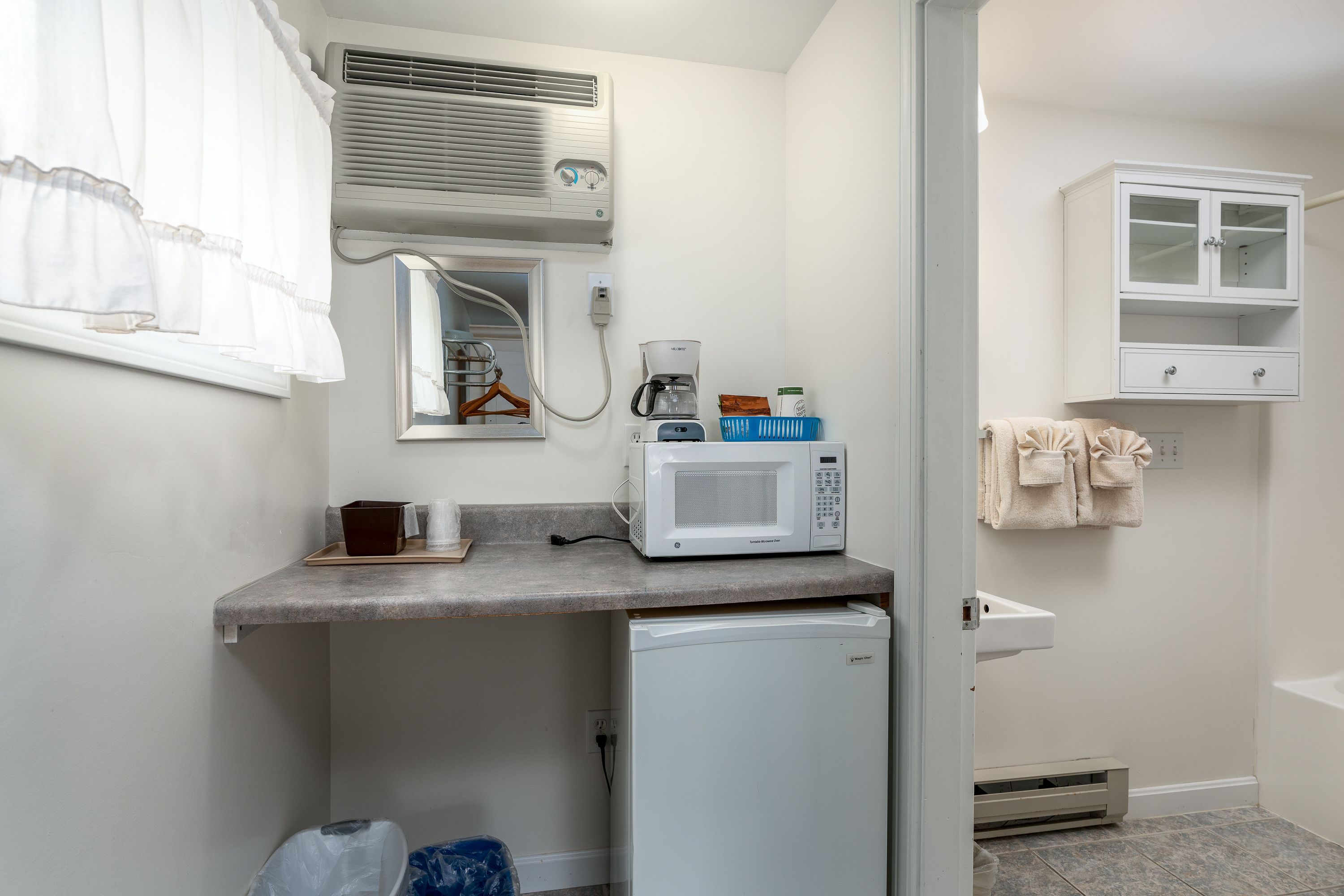 A compact kitchenette with a microwave, coffee maker, and small refrigerator.