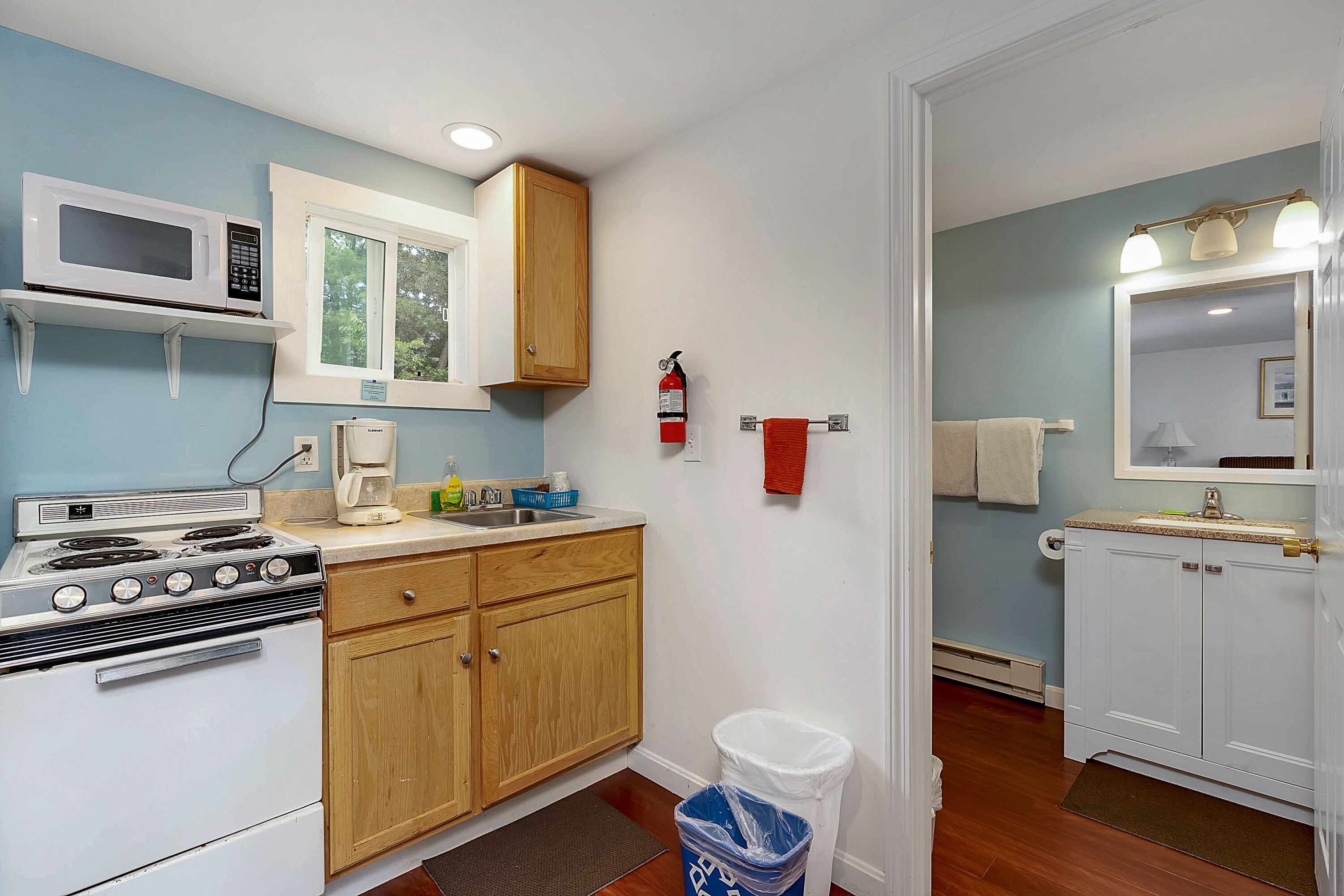 Cocina compacta con estufa, microondas y muebles de madera.