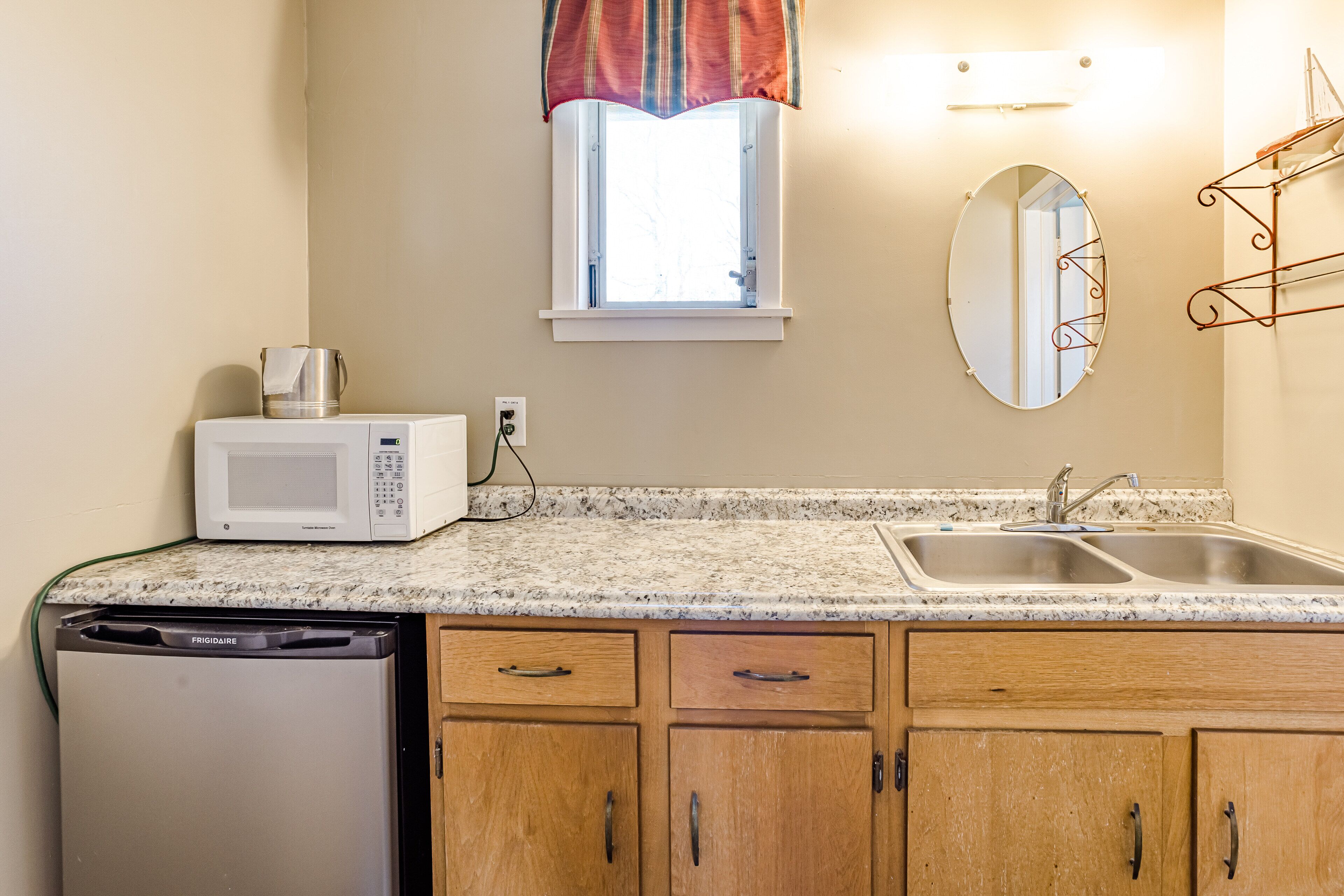 A compact kitchen with a microwave, sink, and wooden cabinets.