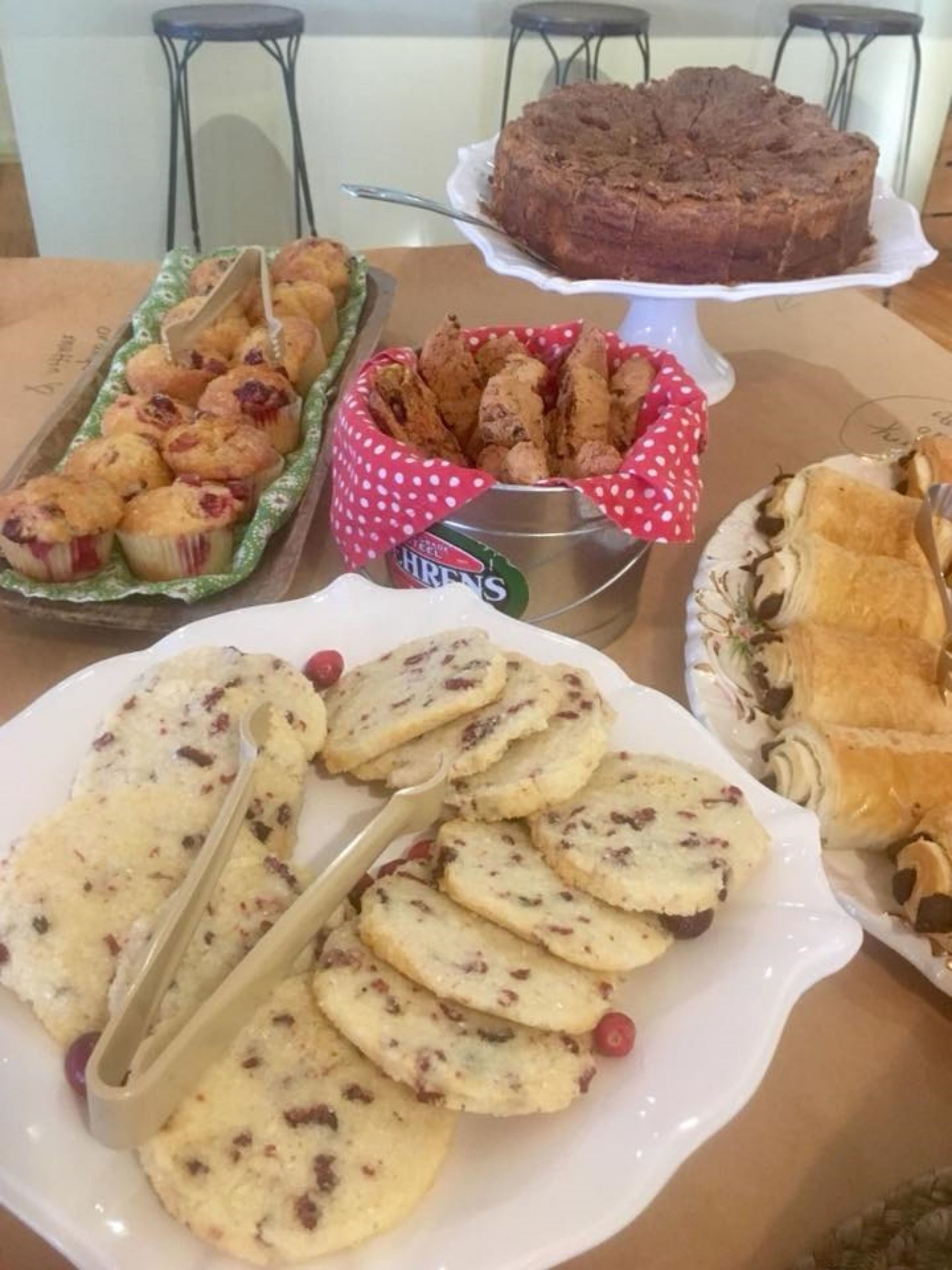 A table with various baked goods including muffins, cookies, and a cake.