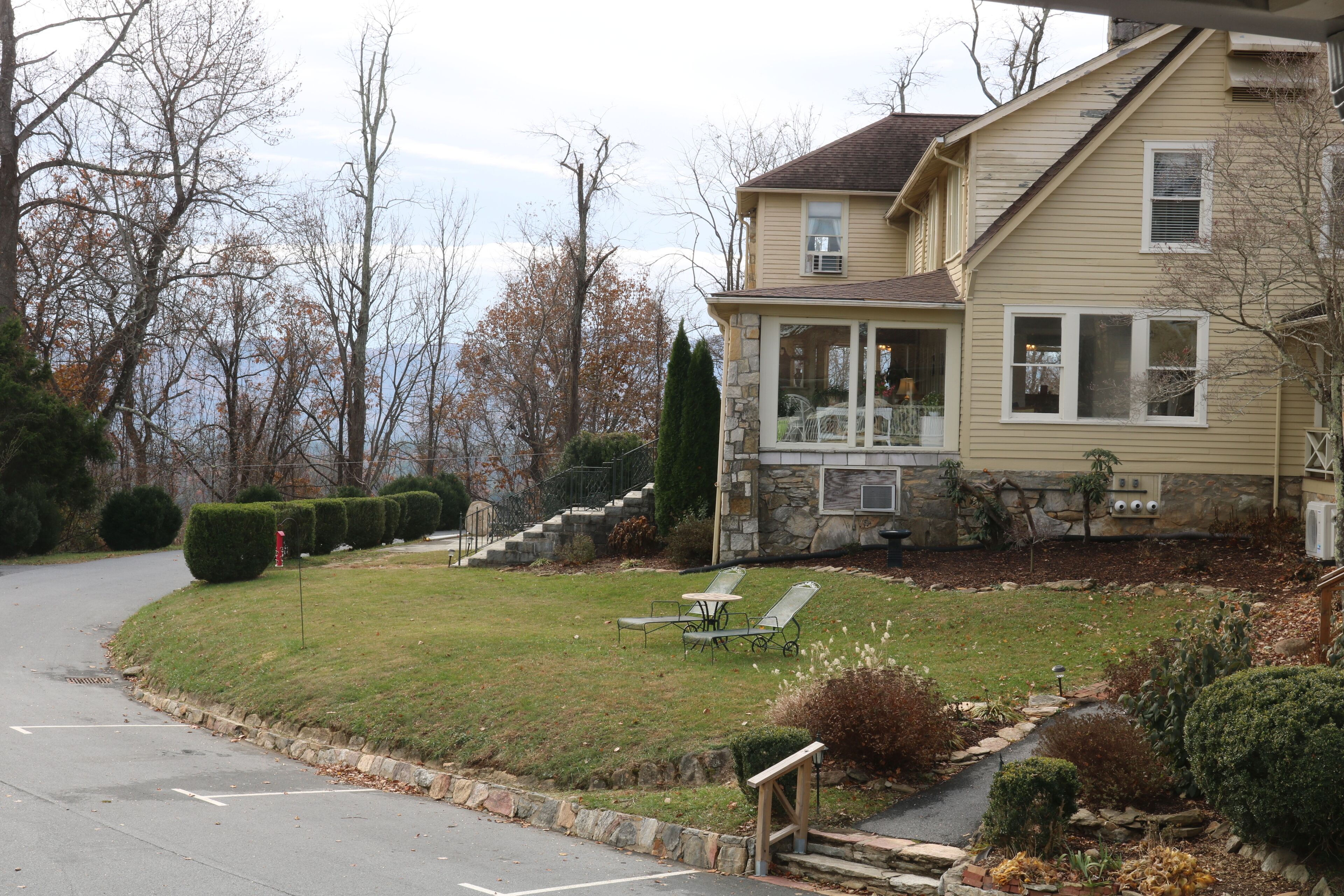 A house with a stone foundation, a front porch, and a well-maintained lawn.