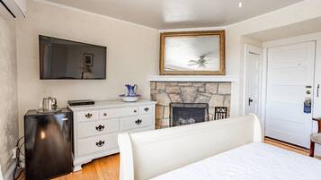 A bedroom with a bed, a dresser, a television, a fireplace, and a door with a sign.