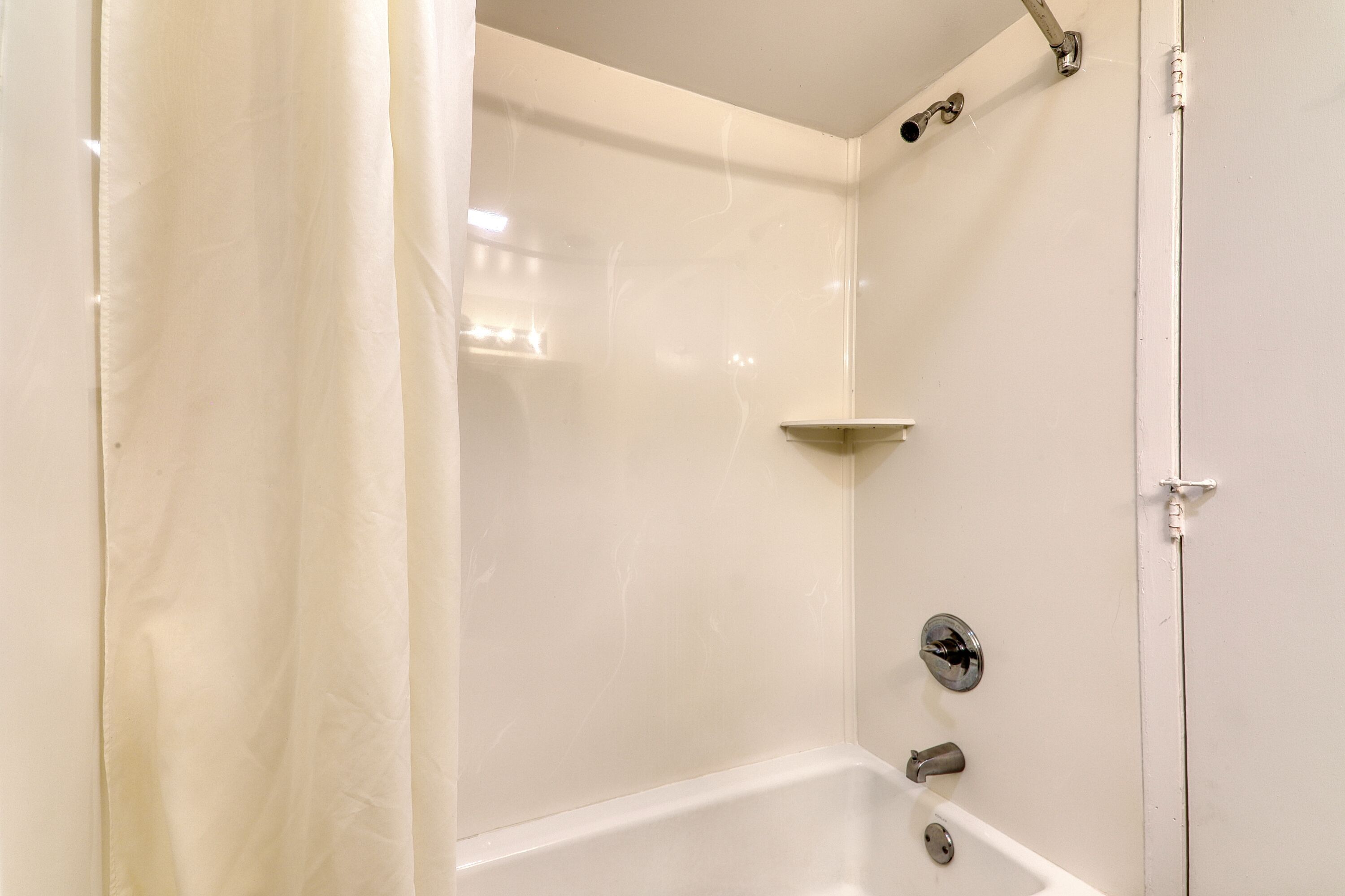 A white bathroom with a shower, a toilet, and a sink.