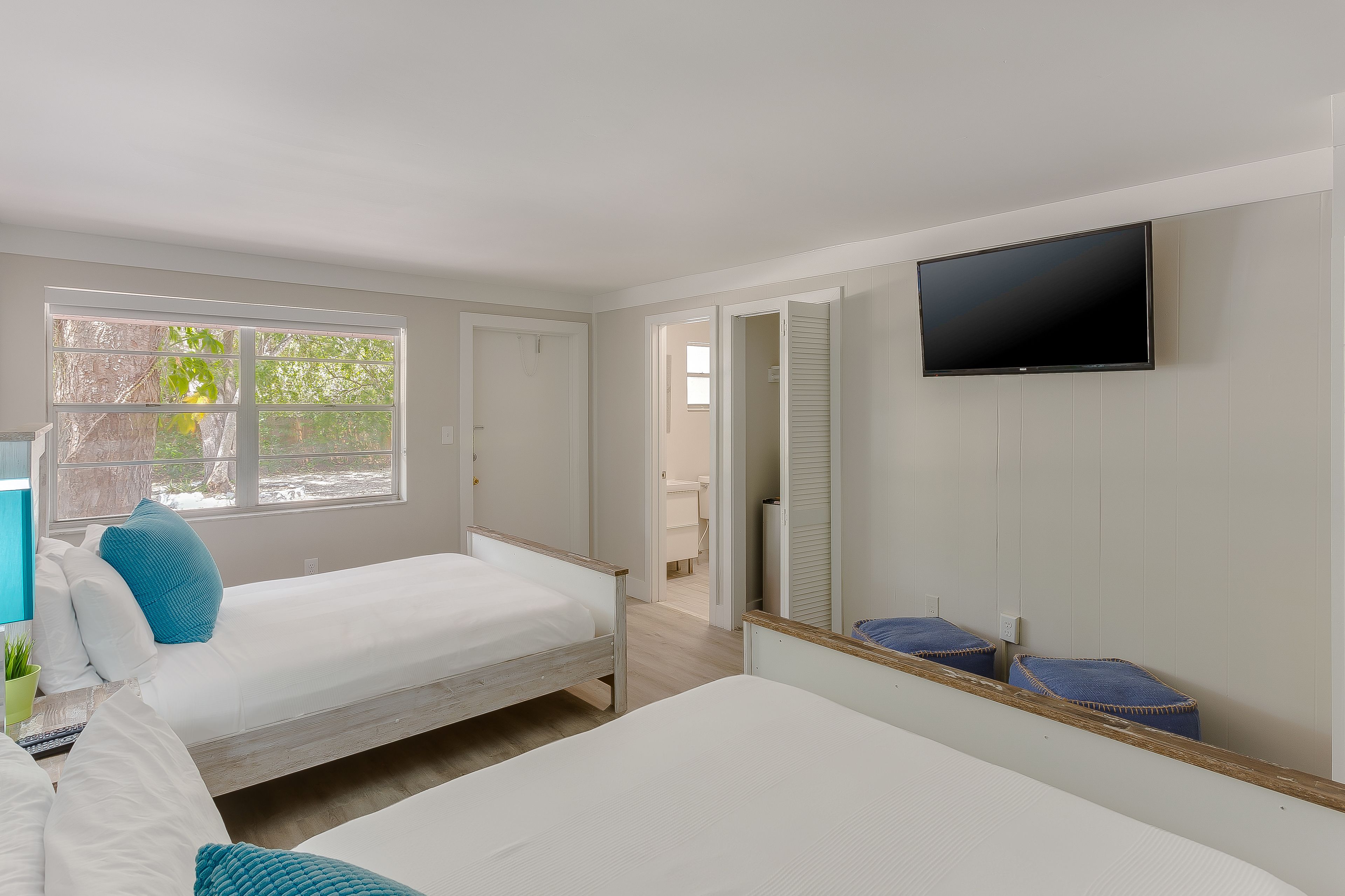 A bedroom with two beds, a TV, and a window.