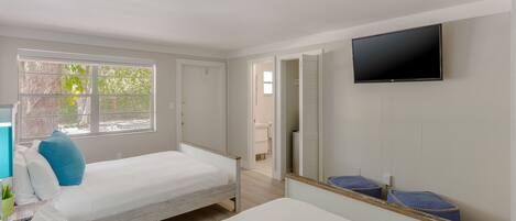 A bedroom with two beds, a TV, and a window.