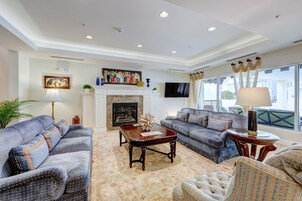 Una sala de estar con chimenea, sofás, televisor y un ventanal con cortinas.