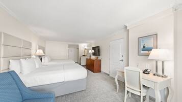 Quarto de hotel com uma cama grande, uma escrivaninha, uma cadeira e uma televisão.