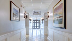 Un pasillo con un letrero que dice 'Lupo Italian Kitchen', flanqueado por obras de arte enmarcadas y apliques de pared.
