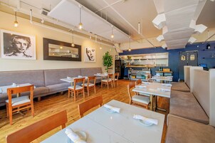 Ein modernes Restaurant mit Holztischen, gepolsterten Sitzgelegenheiten und Pendelleuchten.