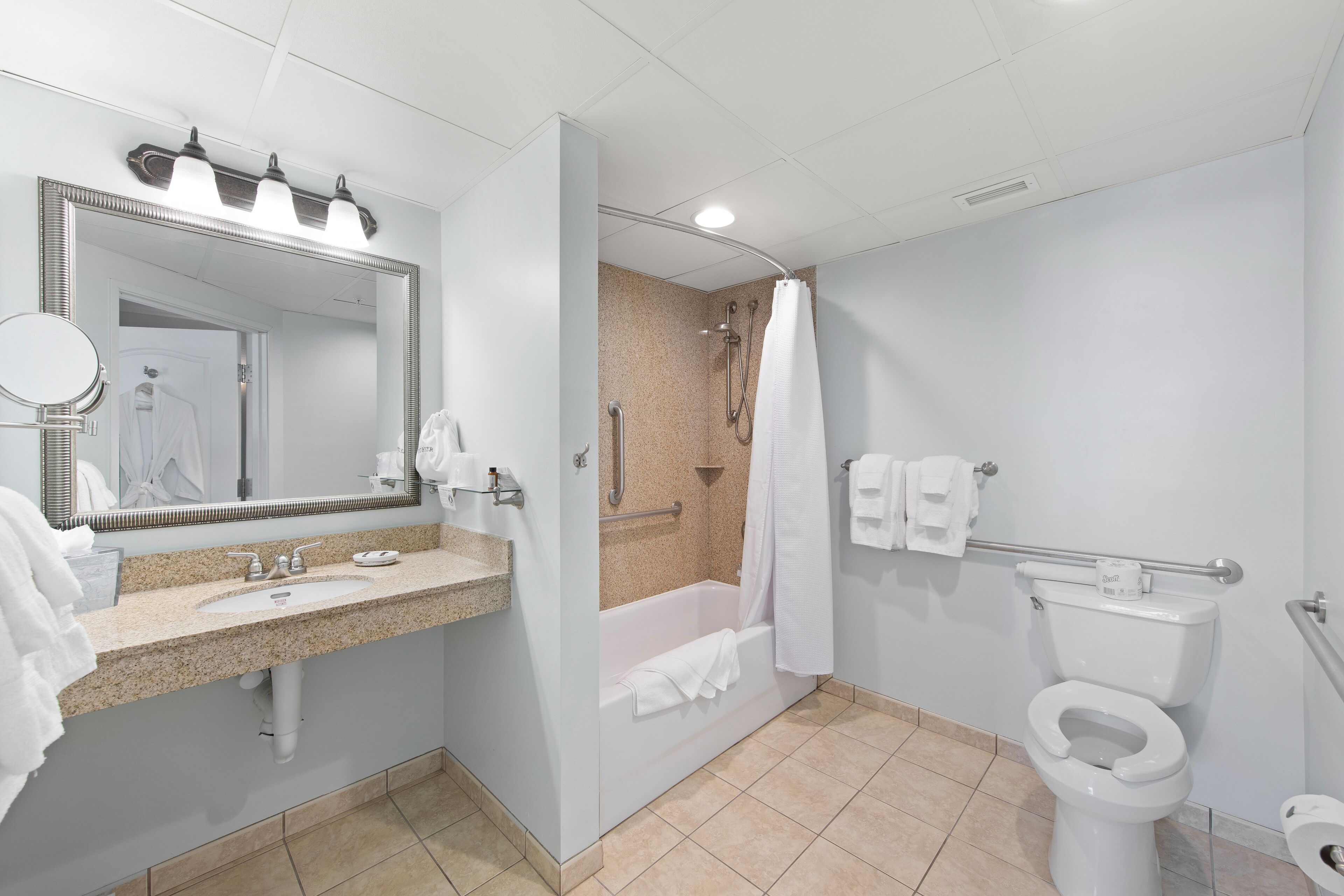 Une salle de bain moderne équipée d’un lavabo, d’un miroir, d’une douche et de toilettes.