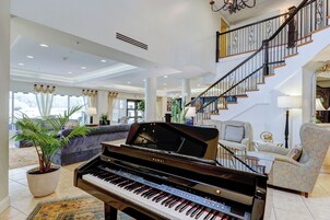 A spacious living room with a grand piano, a staircase, and a comfortable seating area.