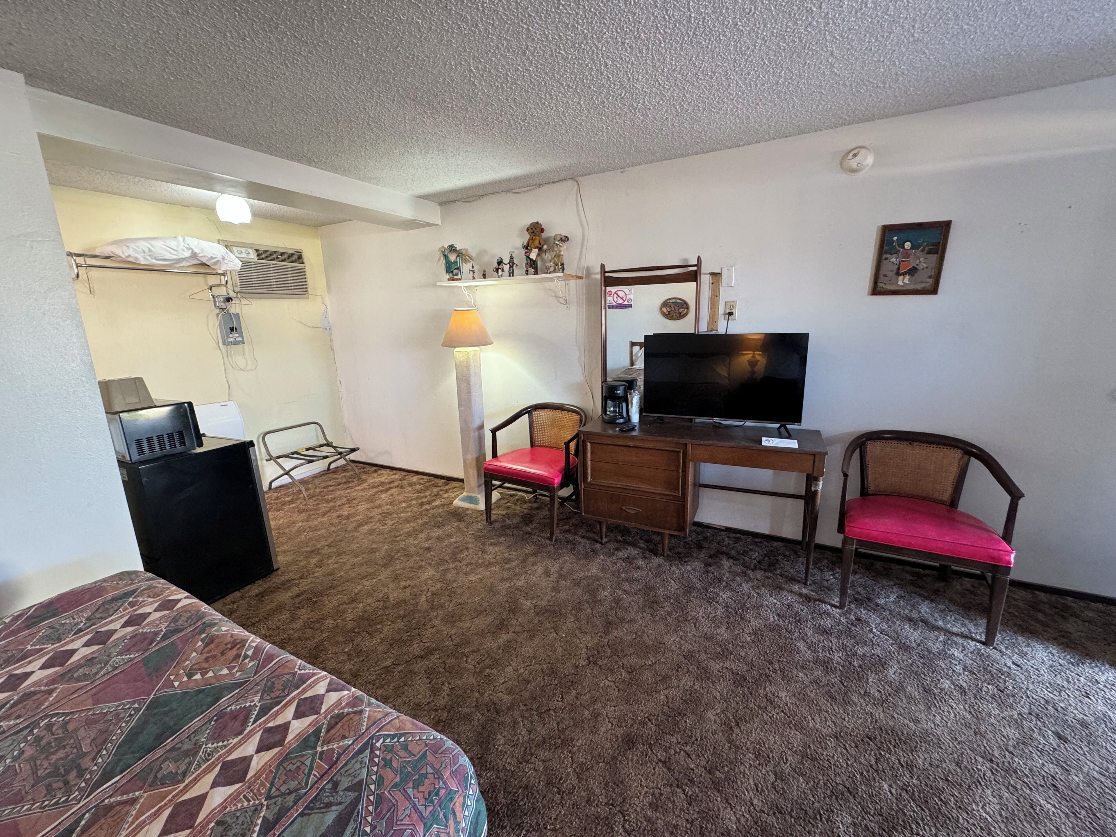 Een hotelkamer met een bed, een bureau met een computer, een televisie en twee stoelen.