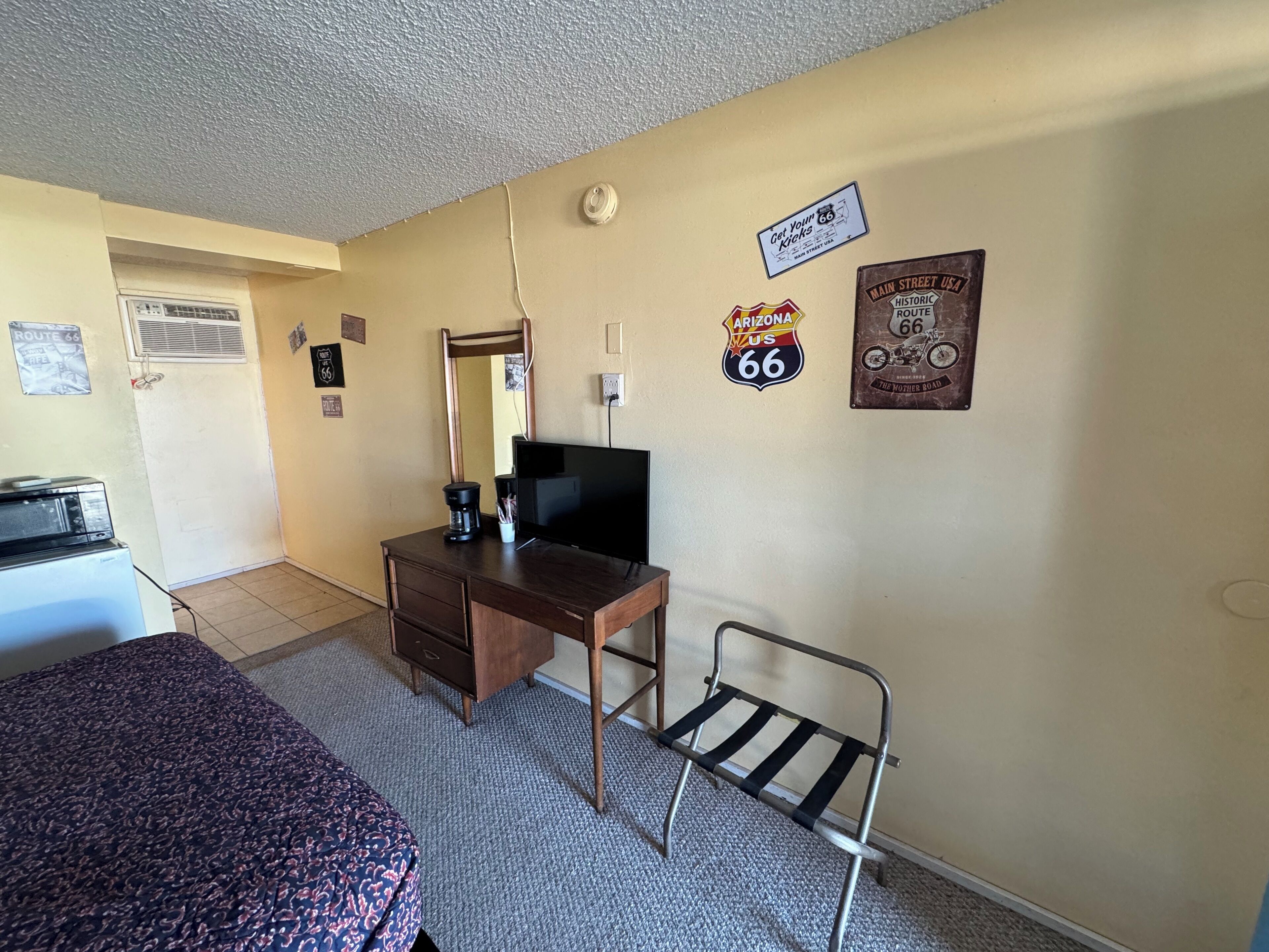 Une chambre comprenant un lit, un bureau avec une télévision, une chaise et des éléments de décoration murale, notamment des panneaux indiquant la Route 66.