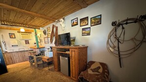 Un interior rústico con techo de madera, una zona de bar y varias decoraciones en las paredes, incluyendo calaveras de animales y cuadros.