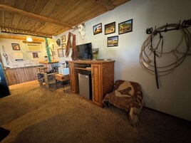 Un interior rústico con techo de madera, una zona de bar y varias decoraciones en las paredes, incluyendo calaveras de animales y cuadros.