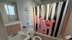 Baño con lavamanos, inodoro y cortina de ducha con un personaje de caricatura.
