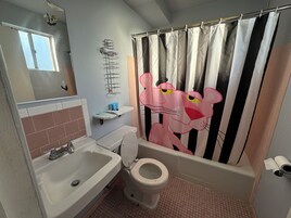 A bathroom with a sink, toilet, and shower curtain featuring a cartoon character.