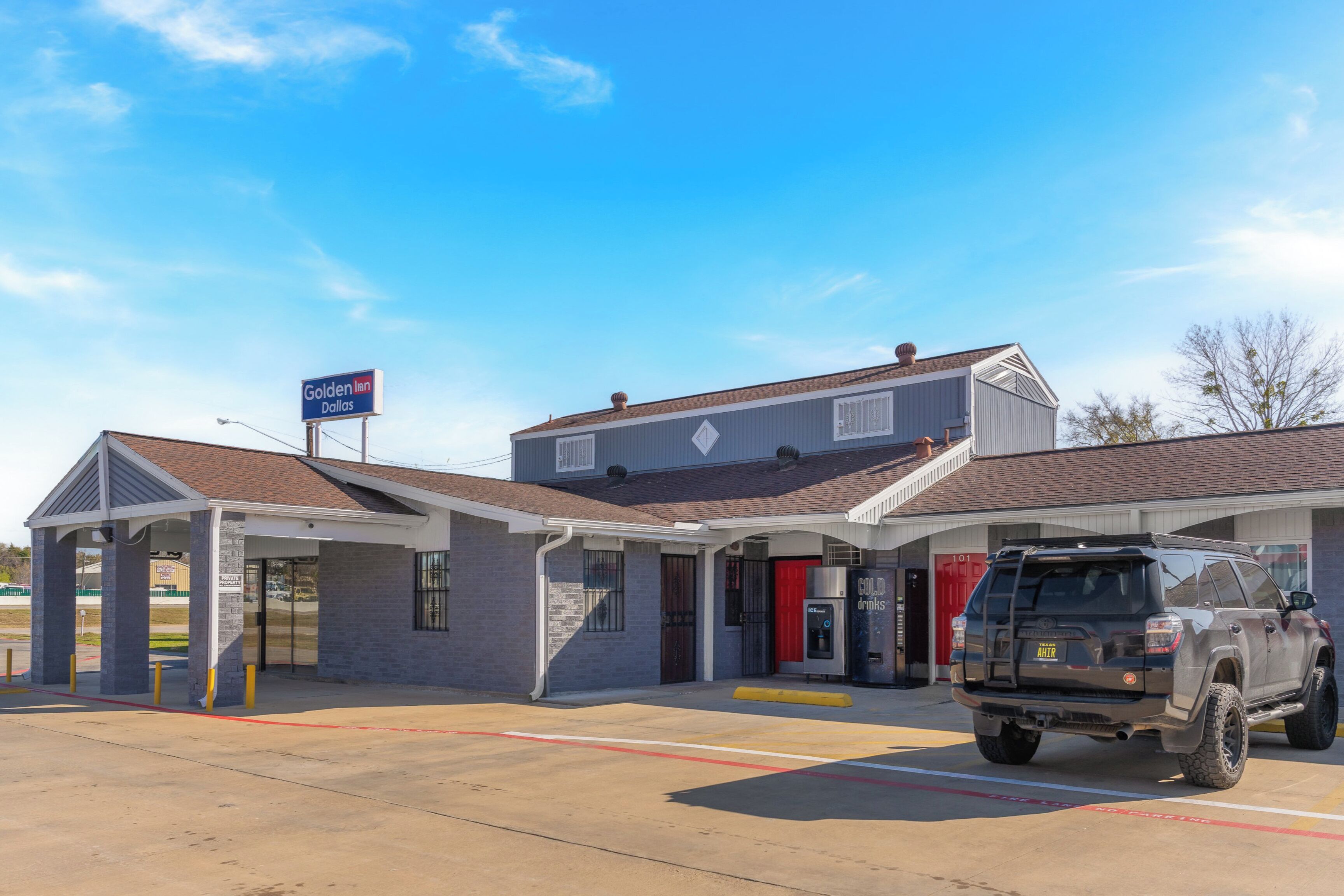 A gas station with a covered entrance, a red door, and a truck parked in the lot.
