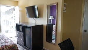 A hotel room with a bed, a wardrobe, a television mounted on the wall, and a mirror. - Village Motor Inn (Austin)