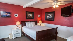 A bedroom with a wooden bed, white bedding, two bedside tables with lamps, and wall art featuring Route 66. - Historic Route 66 Motel (Seligman)