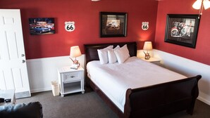 A hotel room with a bed, nightstands, and wall decorations including Route 66 signs. - Historic Route 66 Motel (Seligman)