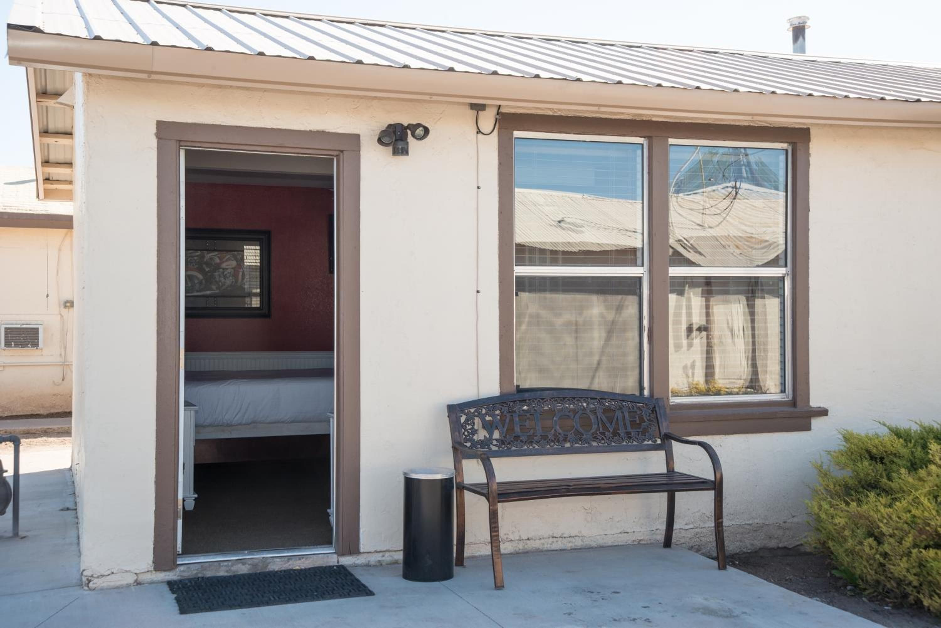 A small building with a single window, a door, and a bench outside.