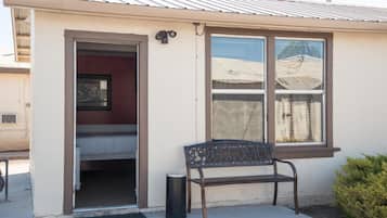 Un petit bâtiment avec une seule fenêtre, une porte et un banc à l’extérieur.