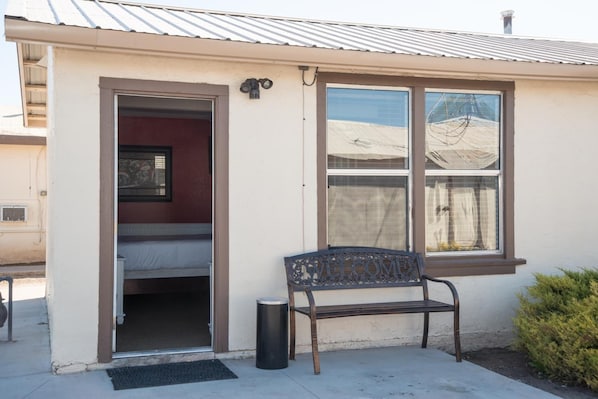 A small building with a single window, a door, and a bench outside. - Historic Route 66 Motel (Seligman)