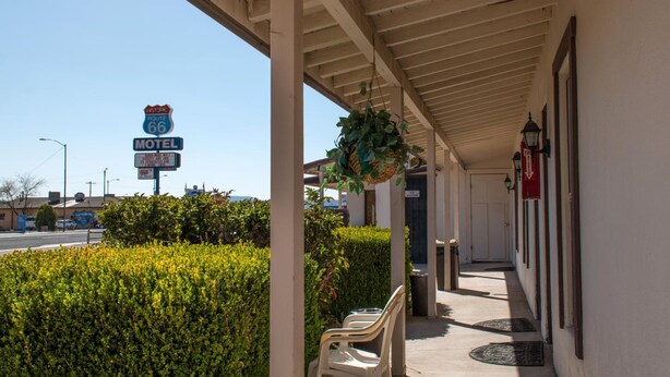 A motel with a covered porch, a sign for Historic Route 66, and a sign indicating a fire extinguisher. - Historic Route 66 Motel (Seligman)