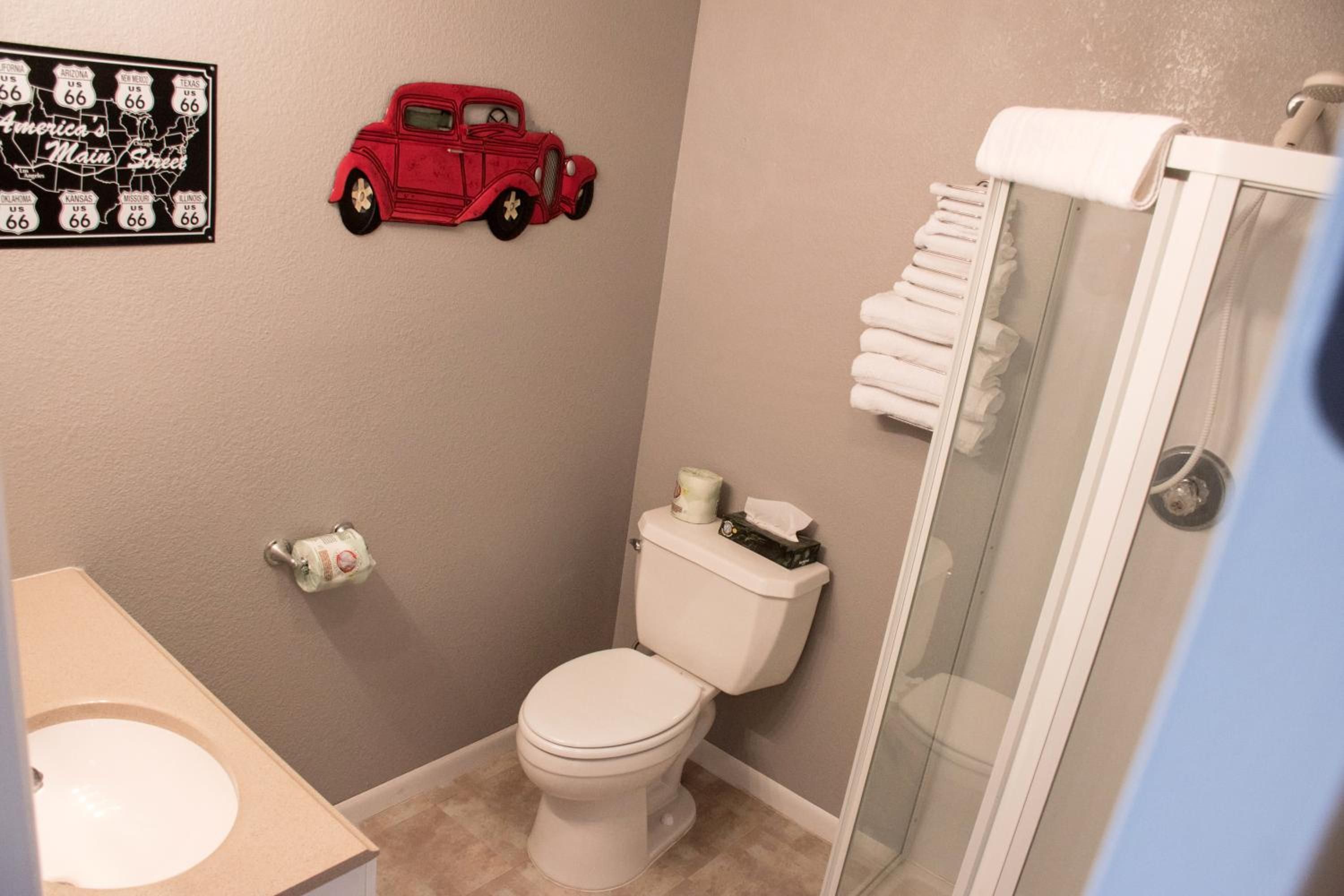 A bathroom with a toilet, a shower, a sink, and a wall-mounted red toy car.