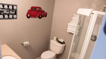 Une salle de bain équipée de toilettes, d’une douche, d’un lavabo et d’une petite voiture rouge fixée au mur.