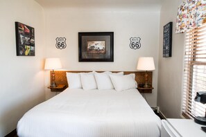 Een hotelkamer met een groot bed, twee bedlampen, een hoofdbord en decoraties met Route 66 thema aan de muren.