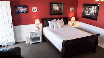 Une chambre d’hôtel équipée d’un lit, de tables de chevet et de décorations murales, notamment des panneaux indiquant le tracé de la Route 66.