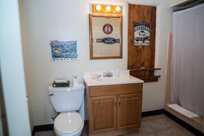A bathroom with a toilet, a sink, a mirror, and a shower curtain.