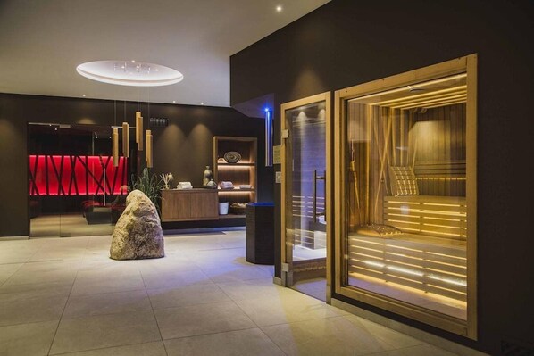 A modern lobby with a reception desk, a large rock sculpture, and a sauna area.