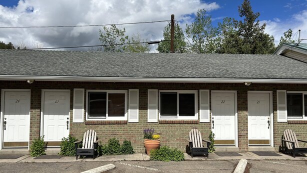 A motel with numbered doors, a parking lot, and outdoor seating. - Columbine INN (Idaho Springs)